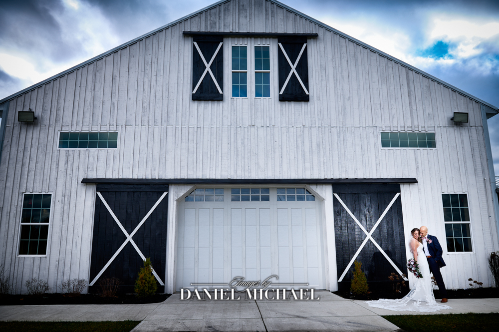 Couple hugging in front of barn