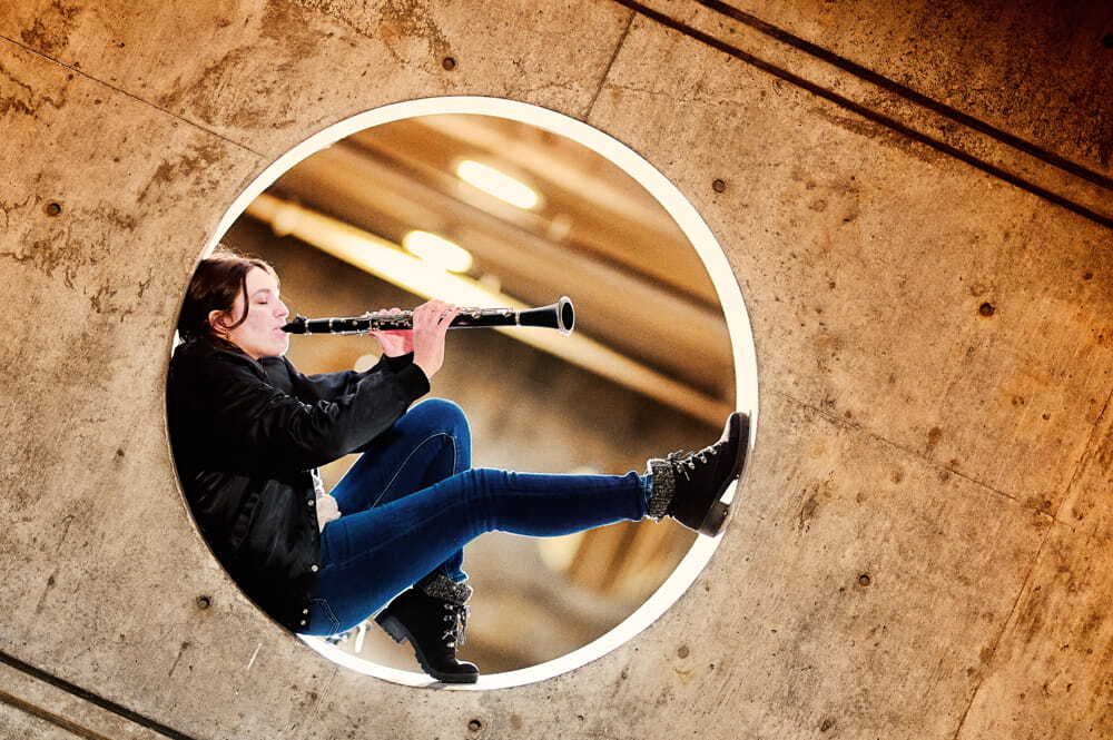 Girl playing instrument while sitting in circular wall cutout